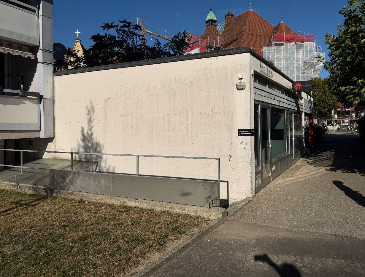 Fussweg rechts am niedrigen weissen Gebäude entlang zum Eingang bei der roten Säule